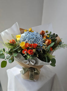 blue hydrangea orange tulips yellow rose orange and yellow rose spray bouquet