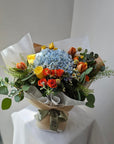 blue hydrangea orange tulips yellow rose orange and yellow rose spray bouquet