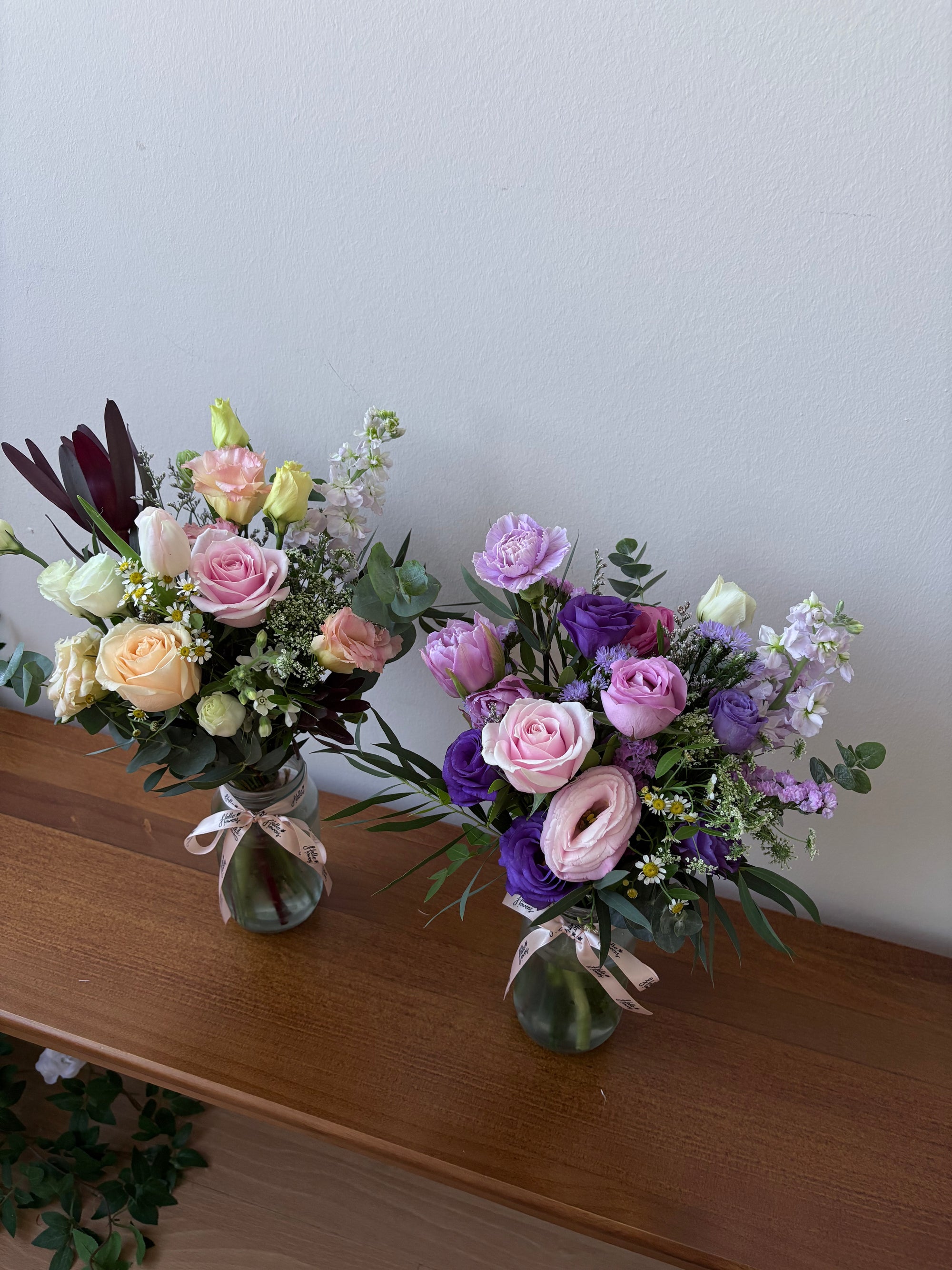 Bouquets of flowers on a wooden surface with a white wall background