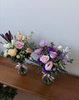 Bouquets of flowers on a wooden surface with a white wall background