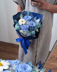 Bouquet of blue flowers with a blue ribbon held by a person.