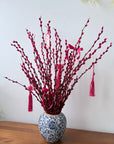 Decorative branch with red ribbons and tassels on a white background