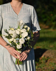 a girl holding bridal bouquet made with white calla lilies, tulips and blue oxypetalum