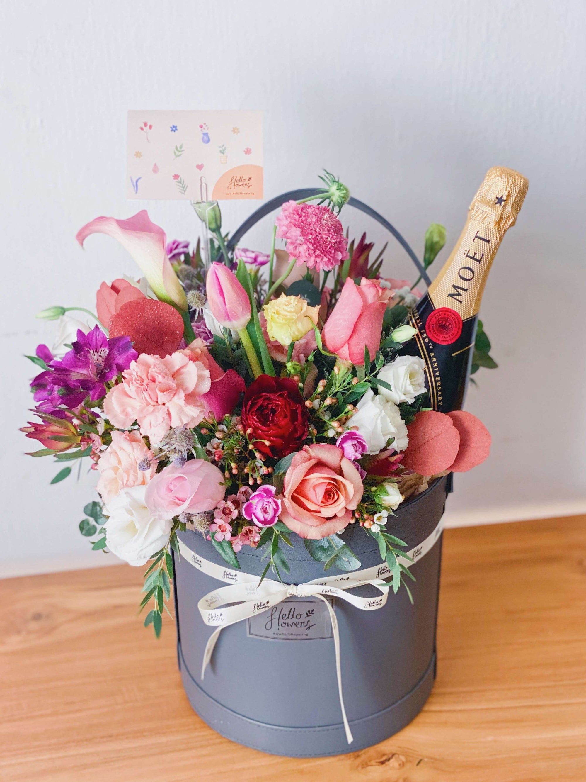 A hamper with combination of aromatic flowers, a bottle of champagne, and a special basket