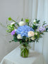 Serene in a Vase arrangement with blue hydrangea, lilacs and white blooms