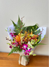 A vibrant bouquet of tropical orchids and foliage, hand-tied and wrapped in burlap.