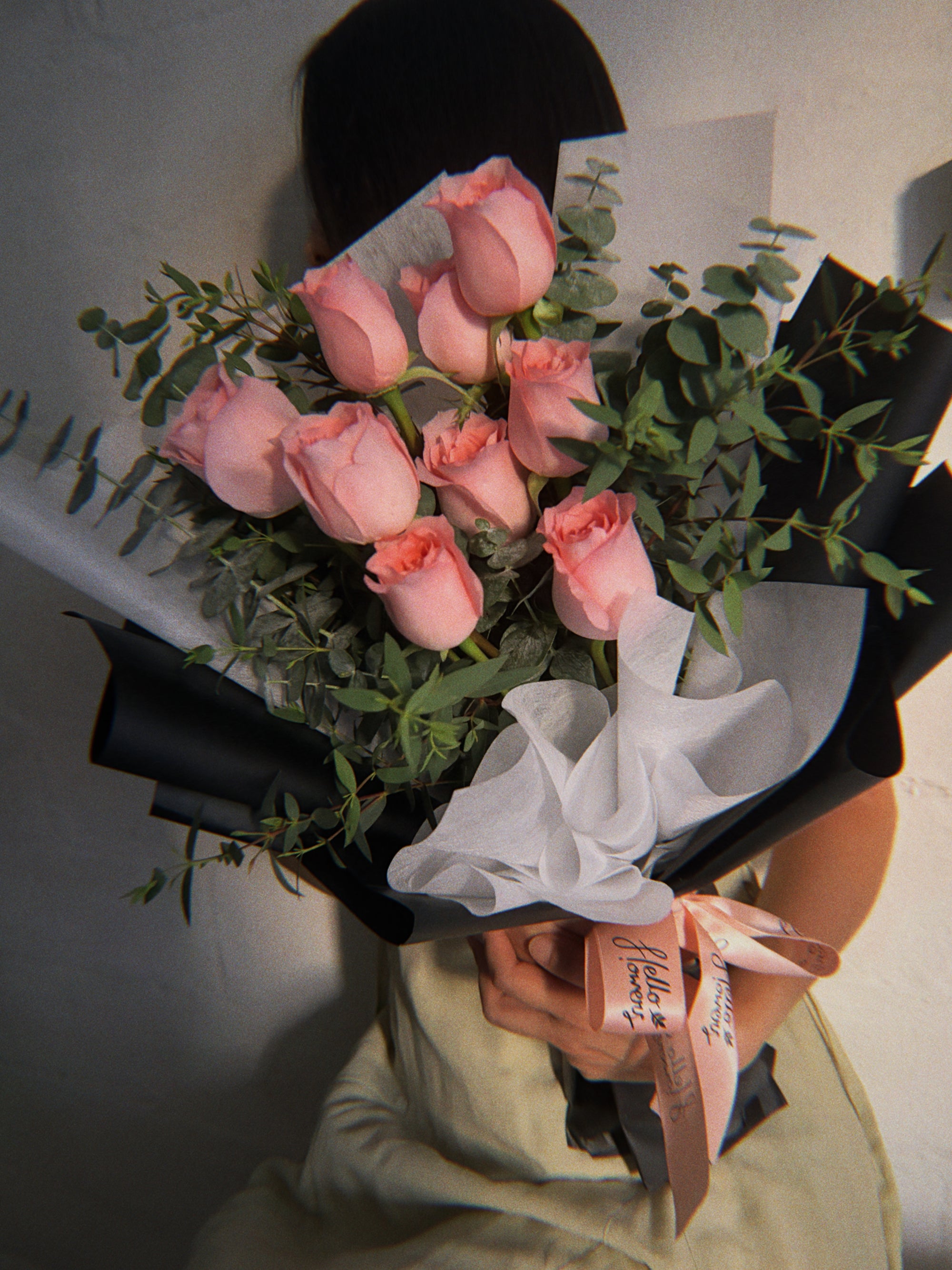 Bouquet of pink roses held by a person wearing a green outfit.